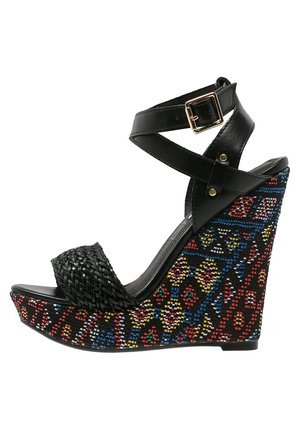Czarna sandałka na koturnie z plecioną fakturą na pasku przy palcach i kolorowymi wzorzystymi akcentami na koturnie. Zapięcie na sprzączkę na pasku wokół kostki.