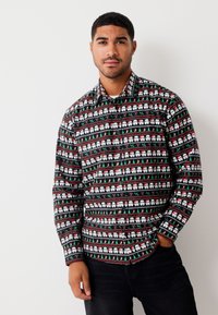 Musta pitkähihaispaita, jossa on toistuva juhlateemainen kuvio valkoisista sotilasklooneista, joulukuusista sekä punaisista ja vihreistä karamellikepeistä.