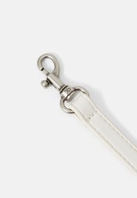 Weißes Lederarmband mit silbernem Metallkarabiner und Ring, ausgestattet mit sauberer Naht entlang der Kanten und geprägtem Logo-Detail.