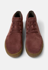 Sneakers in camoscio bordeaux con forma arrotondata, lacci piatti e suole in gomma testurizzate. Tomaia morbida e dettagli in cuciture a contrasto.