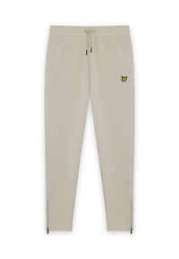 Beige sweatpants med elastisk talje og snor. Har et gult broderet sommerfugl-logo og lynlåse ved anklerne. Glat tekstur.