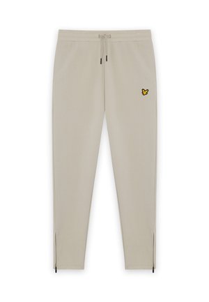 Pantalon de survêtement beige avec taille élastique et cordon de serrage. Présente un logo de papillon brodé jaune et des poignets zippés. Texture lisse.