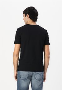 Svart bomull T-skjorte med rund hals, korte ermer og en glatt tekstur; kombinert med lyseblå denimjeans med en klassisk passform.