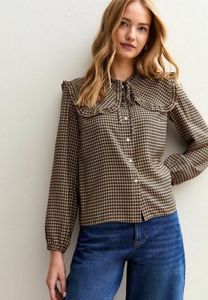 Brown checkered blouse with a large ruffled collar, long sleeves, and button-down front; features textured fabric and a relaxed fit.