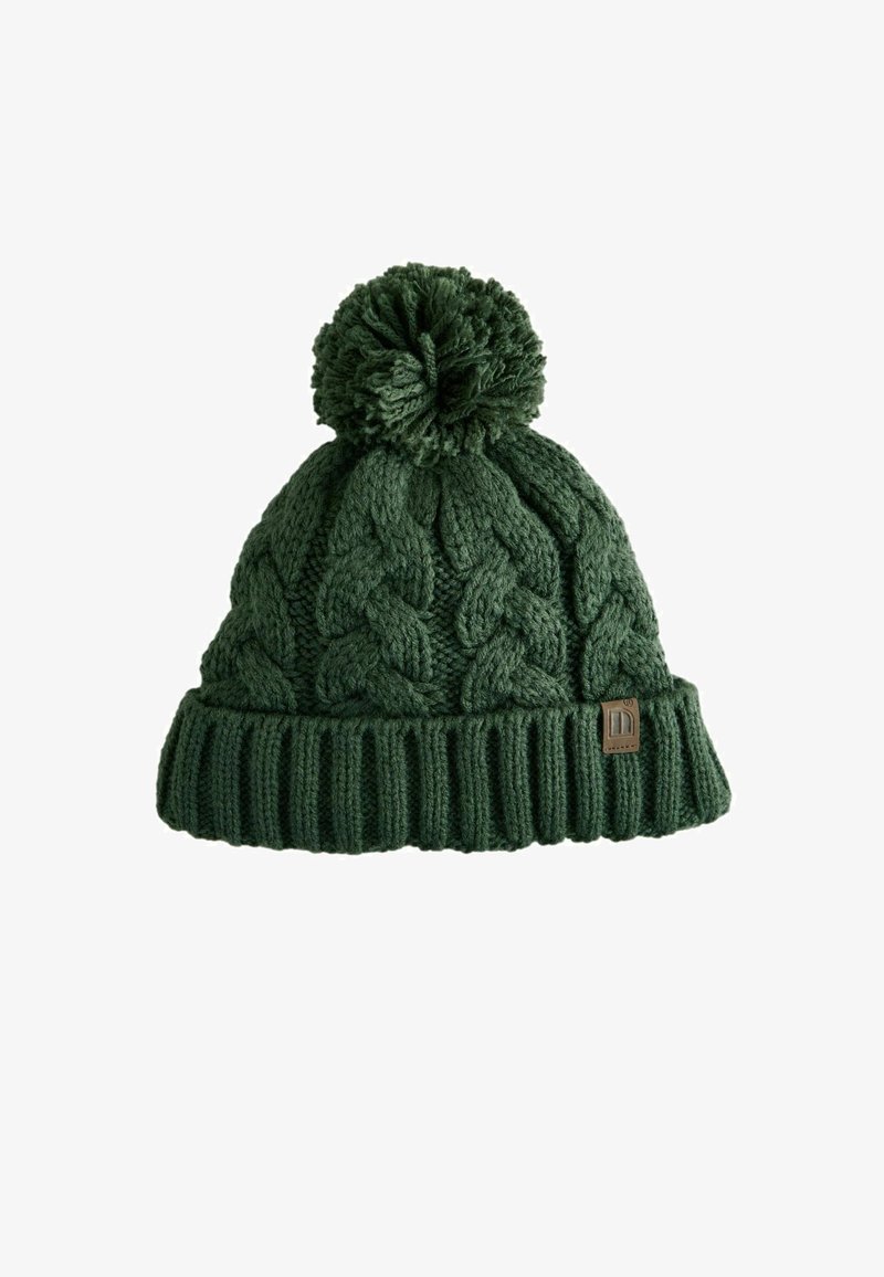 Gebreide groene beanie met een kabelpatroon en een geribde rand. Heeft een grote pompon bovenop en een klein merklabel aan de zijkant.