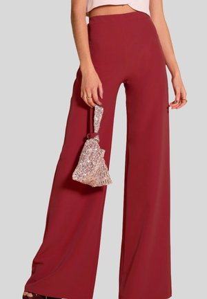 Pantalon large en tissu bourgogne profond, avec une taille haute. Accentué par un petit sac à main en argent scintillant. Texture lisse.