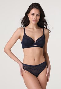 Reggiseno blu navy con pannelli in rete floreale trasparente e coppe con ferretto, abbinato a slip bikini trasparenti con motivo floreale.