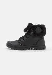 Bottines noires avec col en fausse fourrure, en cuir texturé, bout rond, système de laçage, semelle en caoutchouc robuste et logo circulaire sur le côté.