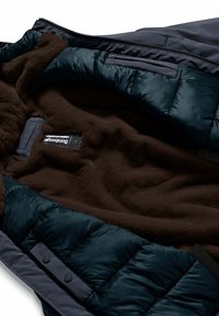 Giacca imbottita con un esterno blu navy, caratterizzata da un morbido rivestimento in pile marrone. Include tasche con zip e un'etichetta del marchio cucita all'interno.