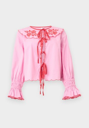 Ροζ μπλούζα με μακριά μανίκια, κόκκινο κεντητό γιακά με λουλούδια, κόκκινες κορδέλες στο μπροστινό μέρος, κυματιστά άκρα και μανσέτες με σούρες και βολάν.