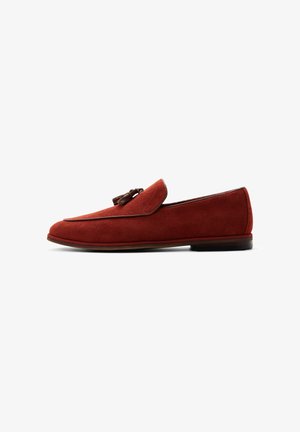 Men’s rust-colored suede loafer with tassel detail, low heel, and brown trim, shown in side profile on white background.