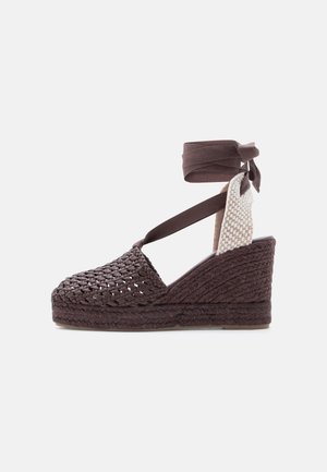 Brun vævet kile-sandal med ankelremme og en tekstureret vævet hælkappe, vist fra indersiden.
