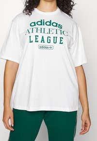 Valkoinen ylisuurikokoinen t-paita, jossa on vihreä "Adidas Athletic League" -teksti ja logo. Klassinen pyöreä kaula-aukko ja lyhyet hihat, valmistettu puuvillasta.