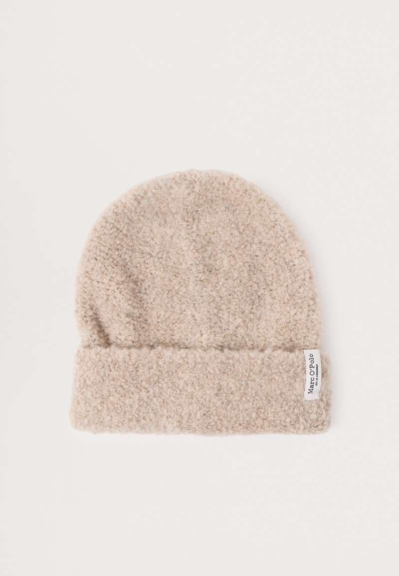 Beige lõngast beanie, millel on pehme ja tekstureeritud pind. Tal on voltitud krae ja väike brändi silt külgedel.
