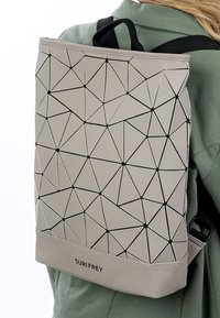 Šedý batoh s geometrickým vzorem a černými doplňky, vyrobený z hladkého materiálu. Má horní rukojeť a nastavitelné černé popruhy.