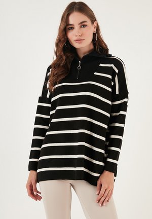 Pull à col haut, avec des rayures horizontales noires et blanches. Fabriqué en maille, coupe décontractée, manches longues et détail de fermeture éclair.