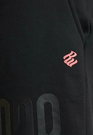 Black sweatshirt featuring textured fabric, a small pink logo on the shoulder, and large black lettering along the bottom hem.