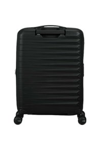 Svart hård resväska med en strukturerad zigzag-design, en utdragbar handtag och fyra hjul för enkel transport.