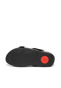 Sandal nero con due cinturini, dotato di suola in gomma testurizzata. Accento circolare rosso noto e logo "fitflop" impresso nella parte inferiore.
