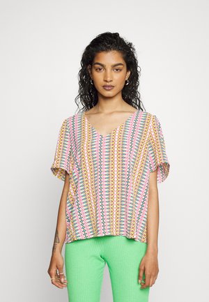 Blusa de mangas curtas, com decote em V, em padrão zig-zag rosa vivo, azul e amarelo. Tecido leve, corte descontraído, com uma textura suave.
