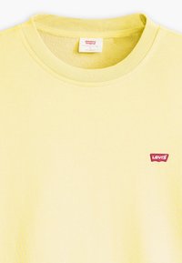 Geel katoenen T-shirt met een geribde halslijn en een klein rood Levi's-logo op de voorkant. Zachte textuur met een eenvoudige ontwerp.