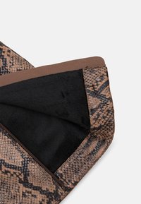Tissu en cuir de serpent marron avec une doublure en polaire noire douce, doté d'une fermeture éclair et d'une finition lisse marron.