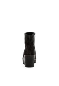 Bottines noires en daim avec une forme arrondie, une fermeture éclair à l'arrière et un talon épais, présentant un détail de couture contrastant autour de la semelle.