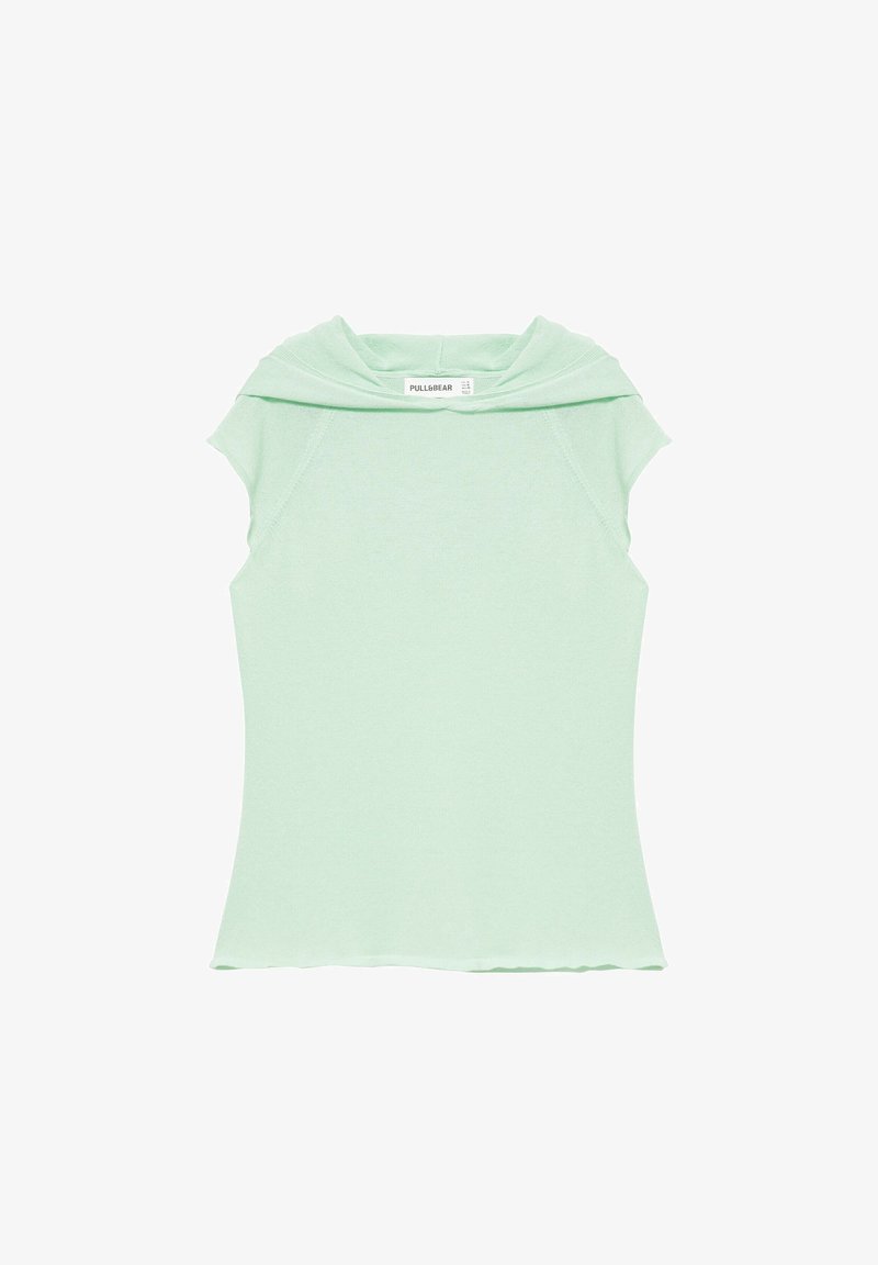 Haut en tricot vert clair sans manches avec un large col plié et une étiquette à l'intérieur de l'encolure sur fond blanc.