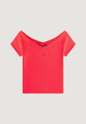 Top rosso a maniche corte con spalle scoperte e un piccolo logo rettangolare centrato sotto la scollatura a V, su uno sfondo chiaro e semplice.