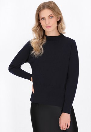 Maglione lavorato a maglia blu navy con collo alto, maniche lunghe e orlo a coste. Texture liscia, silhouette aderente e design rilassato.