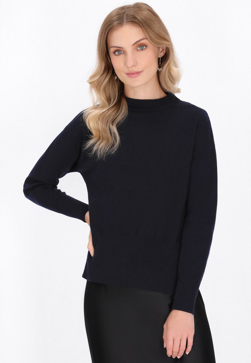 Marineblauer Strickpullover mit hohem Kragen, langen Ärmeln und geripptem Saum. Glatte Textur, taillierte Silhouette und lockerer Schnitt.