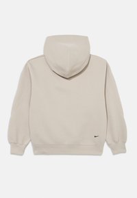 Μπεζ φούτερ με κουκούλα, λεία υφή, ριμπ μανσέτες και τελείωμα, καθώς και μικ ρό μαύρο λογότυπο της Nike στο κάτω δεξί μέρος.