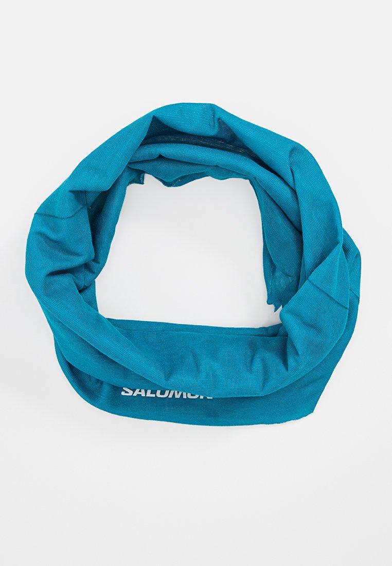 Gaiter de cuello turquesa hecho de tela suave y elástica. Presenta un diseño en bucle con un logo blanco mostrado de manera prominente.
