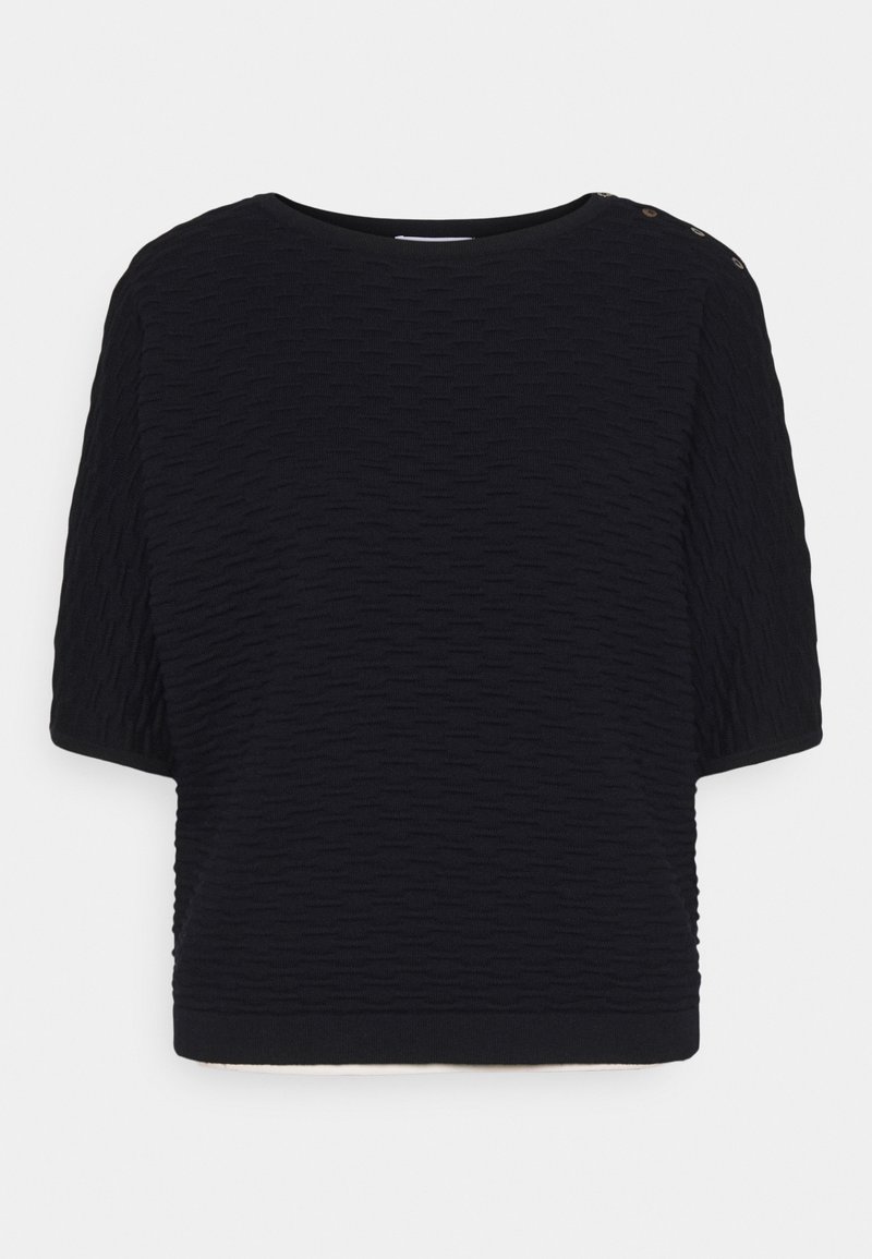 Haut noir en maille texturée à manches courtes avec col rond et trois petits boutons sur l'épaule gauche sur fond blanc.