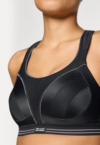 Μαύρο σπορ σουτιέν με υφή, διαθέτει molded cups, αντίθετη ραφή και ελαστική ταινία με λογότυπο. Ιδανικό για αθλητική ένδυση.