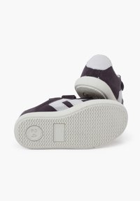 Purple suede sneakers with white accents, featuring a textured rubber sole and a Velcro strap. Flat shape, reinforced toe, and padded heel.