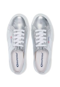 Sneaker metallici argento con lacci bianchi, caratterizzati da una texture liscia e una punta rotonda. Logo del marchio visibile sul lato e sulla soletta.