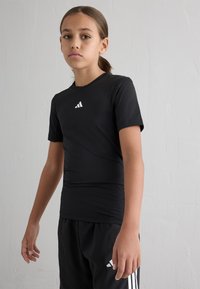 Black athletic t-shirt with short sleeves, smooth texture, featuring white Adidas logo on the chest, paired with black shorts.