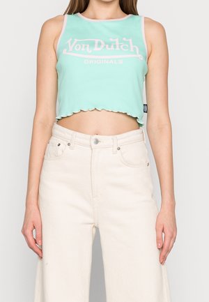 Top corto en verde menta con dobladillo festoneado, que presenta un logo rosa "Von Dutch" en el frente. Combinado con unos jeans de pierna ancha de cintura alta en blanco cremoso.