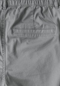 Shorts légers gris avec une taille élastique, dotés d'une poche arrière unique, d'une texture lisse et de détails de couture subtils.