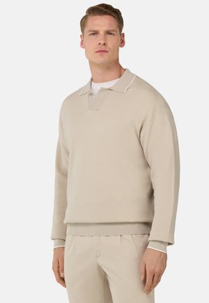 Beige Baumwollpullover mit Lockere Passform, V-Ausschnitt mit Kragen und Rippbündchen an den Ärmeln und am Saum. Mit weißem Akzent am Kragen.