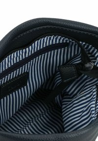 Interno di una borsa in pelle scura con una fodera a righe blu navy e bianche. Presenta una tasca con zip e cinghie in tessuto per l'organizzazione.