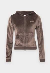 Sweat à capuche marron en velours avec fermeture éclair, poche frontale et poignets côtelés. Dispose d'un petit logo métallique sur le côté gauche de la poitrine. Texture douce.