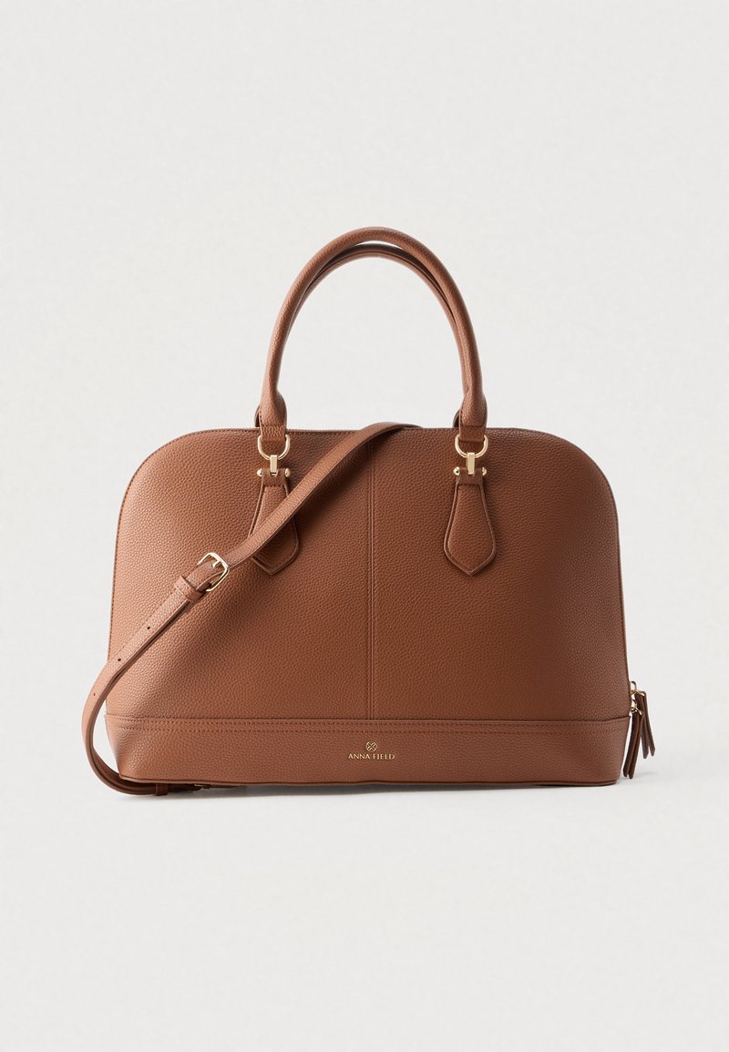 Καφέ τσάντα χειρός από δερμα που έχει υφή, με δύο κορυφαίες λαβές, αποσπώμενο ιμάντα ώμου, χρυσά μεταλλικά στοιχεία και ανάγλυφο λογότυπο στο μπροστινό μέρος.