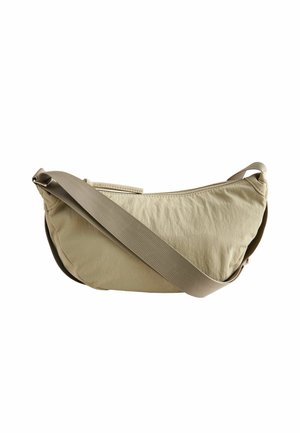 Sac bandoulière marron clair en forme de croissant avec une sangle large en tissu réglable et une fermeture éclair sur le dessus.