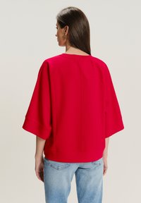Rode oversized sweatshirt met driekwartmouwen, voorzien van een ronde halslijn en een rechte zoom. Gladde katoenen stofmix.