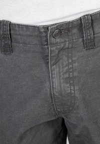 Graue Baumwollhosen mit einem Knopfverschluss, Gürtelschlaufen und dezenten Nähdetails, die eine glatte Textur und ein lässiges Design aufweisen.