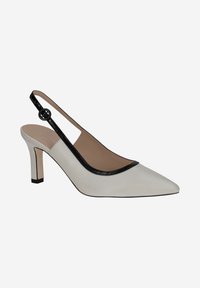 Chaussure slingback à bout pointu en cuir blanc avec une finition noire le long du bord. Équipée d'un talon et d'une boucle ronde sur la sangle.