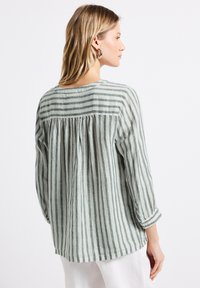 Camicia in lino a righe verde chiaro e bianco, maniche lunghe, collo rotondo, dettaglio a pieghe sul retro, vestibilità comoda, con risvolti alle maniche.