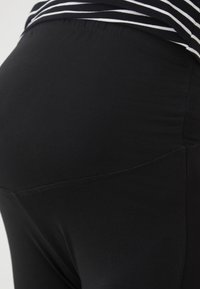 Leggings neri con una texture liscia e una fascia elastica in vita, caratterizzati da una forma attillata e senza motivi o decorazioni visibili.